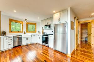 a kitchen with white cabinets and a stainless steel refrigerator at Mtn-View Deck Scenic Conway Log Cabin! in Conway