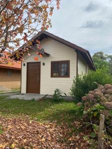 a small white house with a brown door at Chalé do Vale in São Francisco