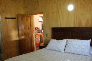 a bedroom with a bed and a door and a microwave at Cabaña Rinconada de Malalcahuello in Malalcahuello