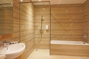 ein Badezimmer mit Dusche, Waschbecken und Badewanne in der Unterkunft Best Western Sagita Hotel Jayapura in Jayapura