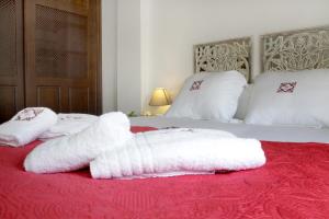 a bed with two white towels on a red blanket at Apartamentos San Fernando 76 in Córdoba