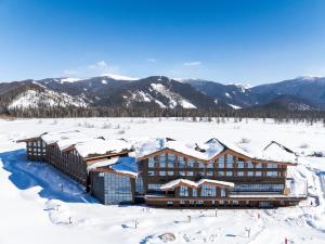 K'u-mu喀纳斯禾木假日度假酒店的一座被雪覆盖的建筑,背景是群山