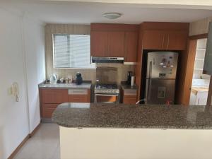 a kitchen with wooden cabinets and a granite counter top at Departamento Deluxe Cumbayá in Quito