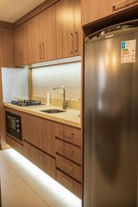 a stainless steel refrigerator in a kitchen with wooden cabinets at apto Casal Canela in Canela