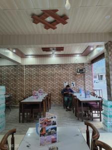 a man sitting at a table in a restaurant at Gokul Guest House By Mero Pahad Stays & camp in Pāndukeshwar +1 photo