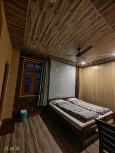 a bedroom with a bed and a wooden ceiling at Gokul Guest House By Mero Pahad Stays & camp in Pāndukeshwar
