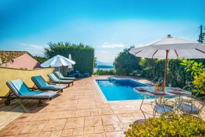 a patio with chairs and an umbrella and a pool at Villa Maistro Cottage by Villa Plus in Ágios Stéfanos