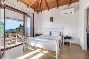 a bedroom with a white bed and a balcony at Villa Anna Lefkas in Póndi +32 photos