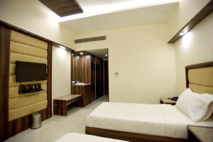 a hotel room with a bed and a television at Hotel Sach Regency in Anand