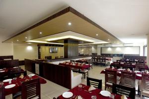 a dining room with red tables and chairs in a restaurant at Hotel Sach Regency in Anand