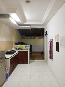 a large kitchen with a large white tile floor at Ngijo Homestay Kost TaniaAlexa in Srondolwetan +2 photos