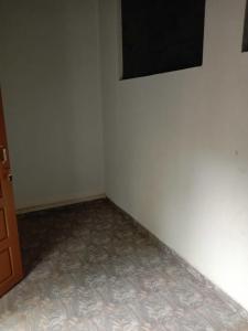 an empty room with a white wall and a television at East home in Kottiyam