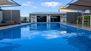 a swimming pool with blue water in front of a building at Beachfront Nautilus in Rockingham