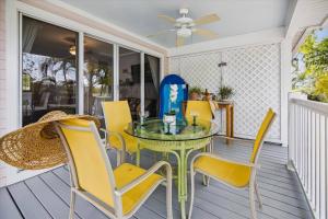 a glass table and yellow chairs on a porch at Bogeys Retreat by AvantStay Golfers Retreat w Shared Pool Month Long Stays Only in Stock Island