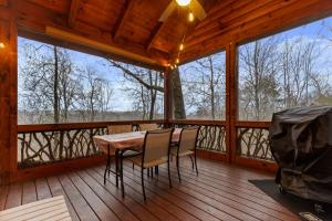 a wooden porch with a table and chairs on a deck at Tree Top Hideaway - Private with Games Firepit More in Blue Ridge
