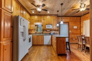 a kitchen with a white refrigerator and wooden cabinets at Tree Top Hideaway - Private with Games Firepit More in Blue Ridge
