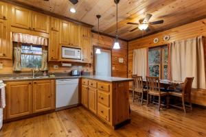 a kitchen with wooden cabinets and a dining table at Tree Top Hideaway - Private with Games Firepit More in Blue Ridge