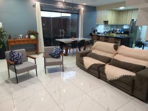 a living room with a couch and chairs and a kitchen at Casa Ampla COP30 in Belém