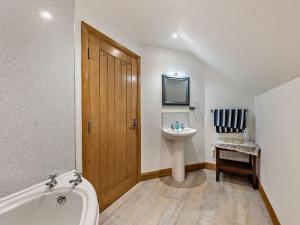 a bathroom with a tub and a sink and a tv at 3 Bed in Fairbourne 77304 in Arthog +15 photos