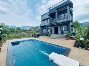 a house with a swimming pool in front of a house at Grey Magic Villa in Karjat