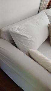 Una cama con sábanas blancas y almohadas. en Casa San Isidro, en San Isidro