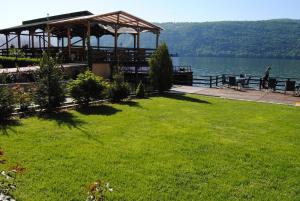 a grassy area with a gazebo next to a lake at Pension La Ponton in Eşelniţa