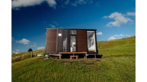 RuawaroMighty Tiny House 1 by Tiny Away的坐在田野上的小房子