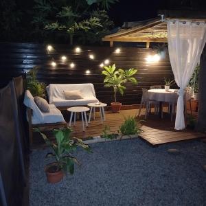a patio with a couch and a table and lights at La Cas'Aline in La Saline les Bains