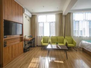 a hotel room with green chairs and a television at GreenTree Inn Hebei Cangzhou Huangye Development Zone in Huanghua
