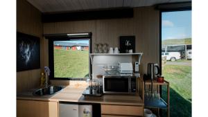 una cucina con forno a microonde, lavandino e finestra di Mighty Tiny House 2 by Tiny Away a Ruawaro