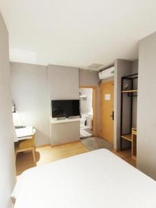 a bedroom with a bed and a desk and a television at Vatica Hotel Hefei Yaohai Longgang Subway Station in Hefei