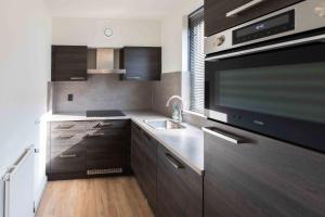 a kitchen with wooden cabinets and a sink and a microwave at Lake-nature Villa 3 Bedrooms, Sleeps 7 in Ewijk