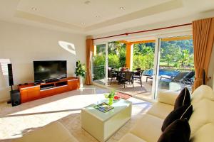 Una sala de estar con un sofá y un televisor. en Blue Chill private Pool Villa - Koh Chang, en Ko Chang