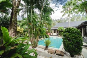a swimming pool in front of a house with palm trees at Villa Banyak | Luxury 4Br villa with nice terrace and personal playground in Ban Saiyuan (1)