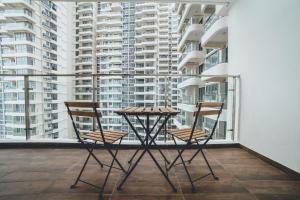 two chairs and a table on a balcony with tall buildings at Danga Bay Coastal Comfort 3BR 8Pax w 3Balcony by Our Stay in Johor Bahru