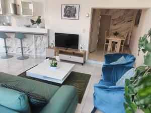 a living room with two blue chairs and a television at Bel appartement confortable Mons in Mons