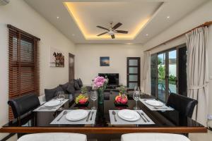 Una sala de estar con una mesa de comedor con sillas. en Villa Kaheru | 3 bedroom priavate pool villa | Kokyang Estate, en Nai Harn Beach