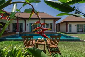 dos sillas y una mesa frente a una casa en Villa Kaheru | 3 bedroom priavate pool villa | Kokyang Estate, en Nai Harn Beach
