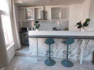 a kitchen with a counter with three stools at Bel appartement confortable Mons in Mons