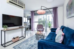 un soggiorno con un divano blu e una TV di Charming 1BR Apt w Balcony In the Heart of TLV with Mamad by Sea N' Rent a Tel Aviv