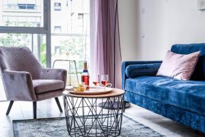 un soggiorno con un divano blu e un tavolo di Charming 1BR Apt w Balcony In the Heart of TLV with Mamad by Sea N' Rent a Tel Aviv