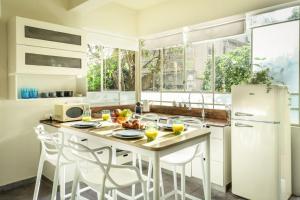 Serene Retreat with Lush Garden في تل أبيب: مطبخ مع طاولة مع كراسي وثلاجة +11 صورة