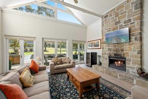 a living room with a large stone fireplace at Brokenback Vineyard Homestead in Pokolbin