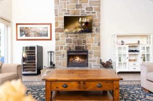 a living room with a fireplace and a wooden coffee table at Brokenback Vineyard Homestead in Pokolbin