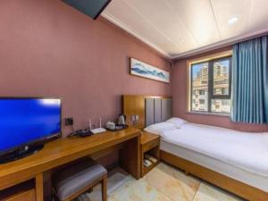 a room with a bed and a desk with a television at FERONIA Hotel Gansu Lanzhou Chengguan District Gannan Road in Lanzhou