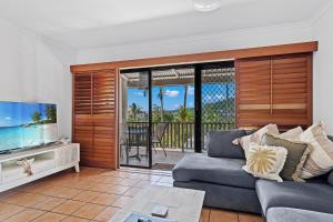 een woonkamer met een bank en een flatscreen-tv bij Sunset Oasis in Airlie Beach