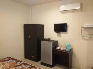 a room with a refrigerator and a tv on the wall at Raisubsomboon Resort in Ban Don Wan