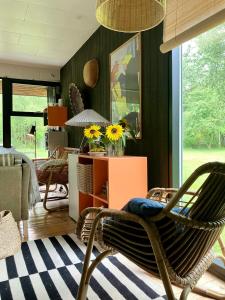 sala de estar con silla y mesa con girasoles en House In The Woods Near Beach With Peaceful Vibes, en Saeby