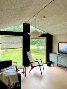 sala de estar con sofá, silla y TV en House In The Woods Near Beach With Peaceful Vibes, en Saeby