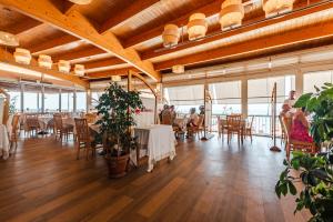 a dining room with tables and chairs and windows at Aragosta Hotel in Durrës